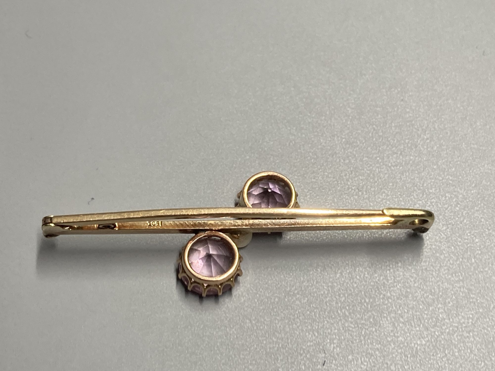 An early 20th century 15ct and three stone pink topaz and seed pearl set crossover bar brooch, 50mm, gross 4.4 grams.